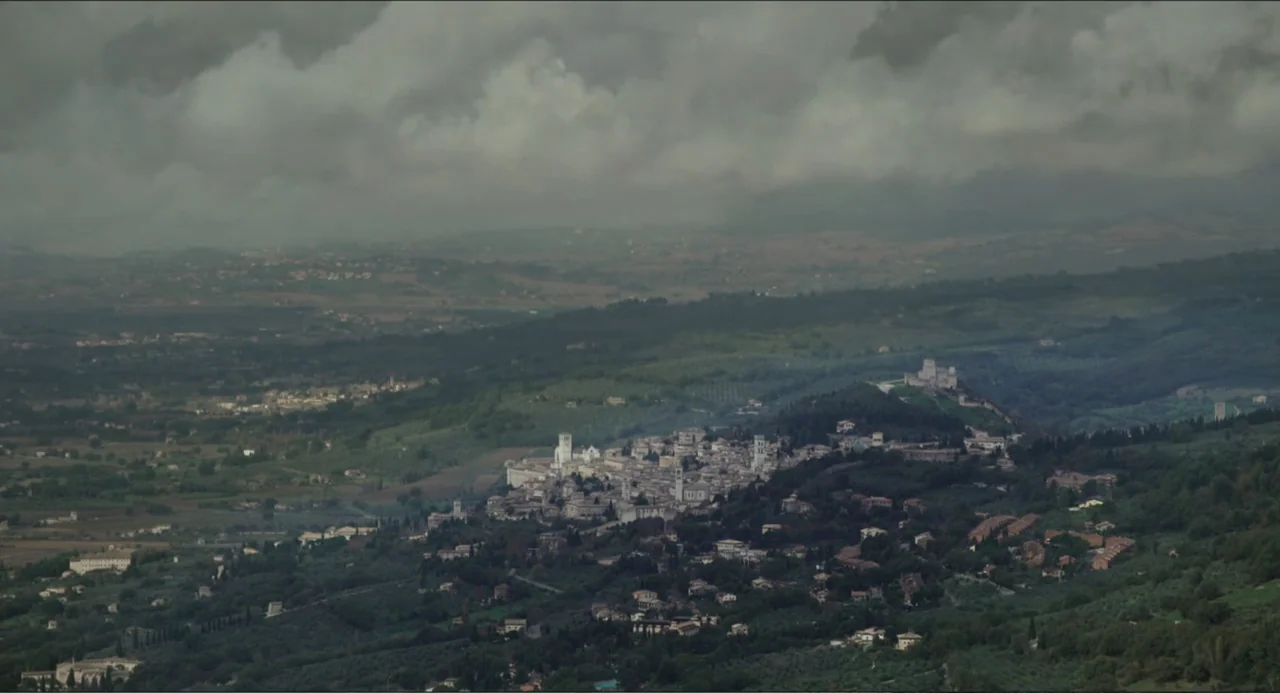 Pope Francis: A Man of His Word (2018) movie still: establishing — A wide aerial view of an ancient town nested in a lush green valley. Rolling…