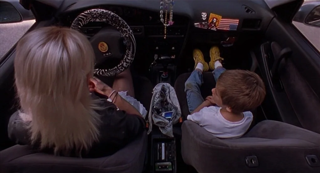 The Heart Is Deceitful Above All Things (2004) movie still: medium — A view inside a car from the perspective of the backseat. The woman drives…