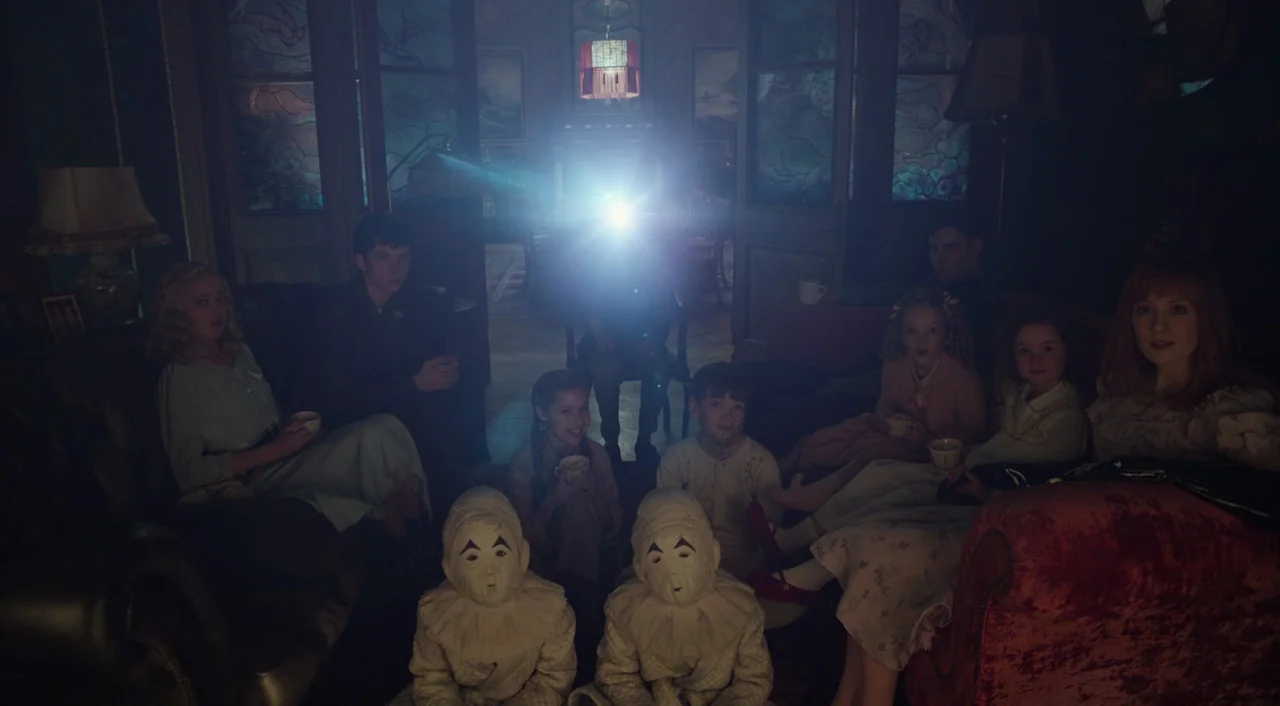 Miss Peregrine’s Home for Peculiar Children (2016) movie still: wide — A dimly lit room holds a group of people watching a bright projector screen.…