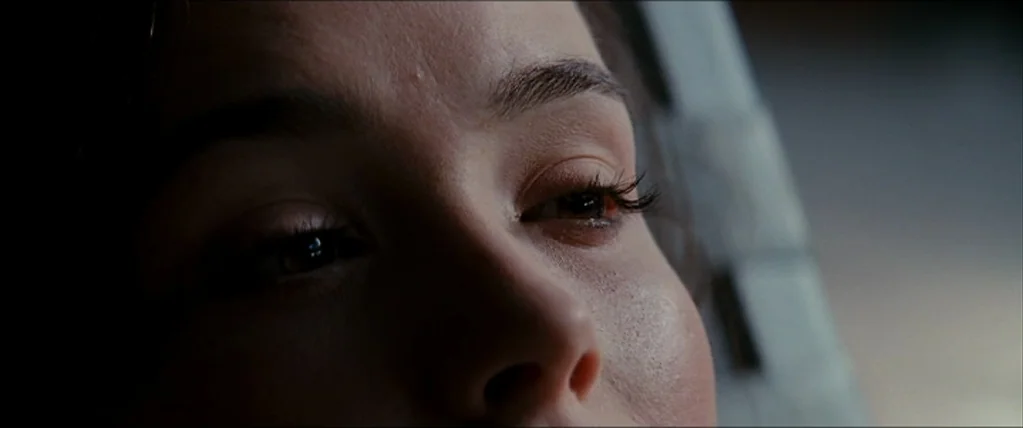 Inception (2010) movie still: closeup — A close-up reveals the side of a person's face inside a vehicle cabin. The subject gazes out toward a window…