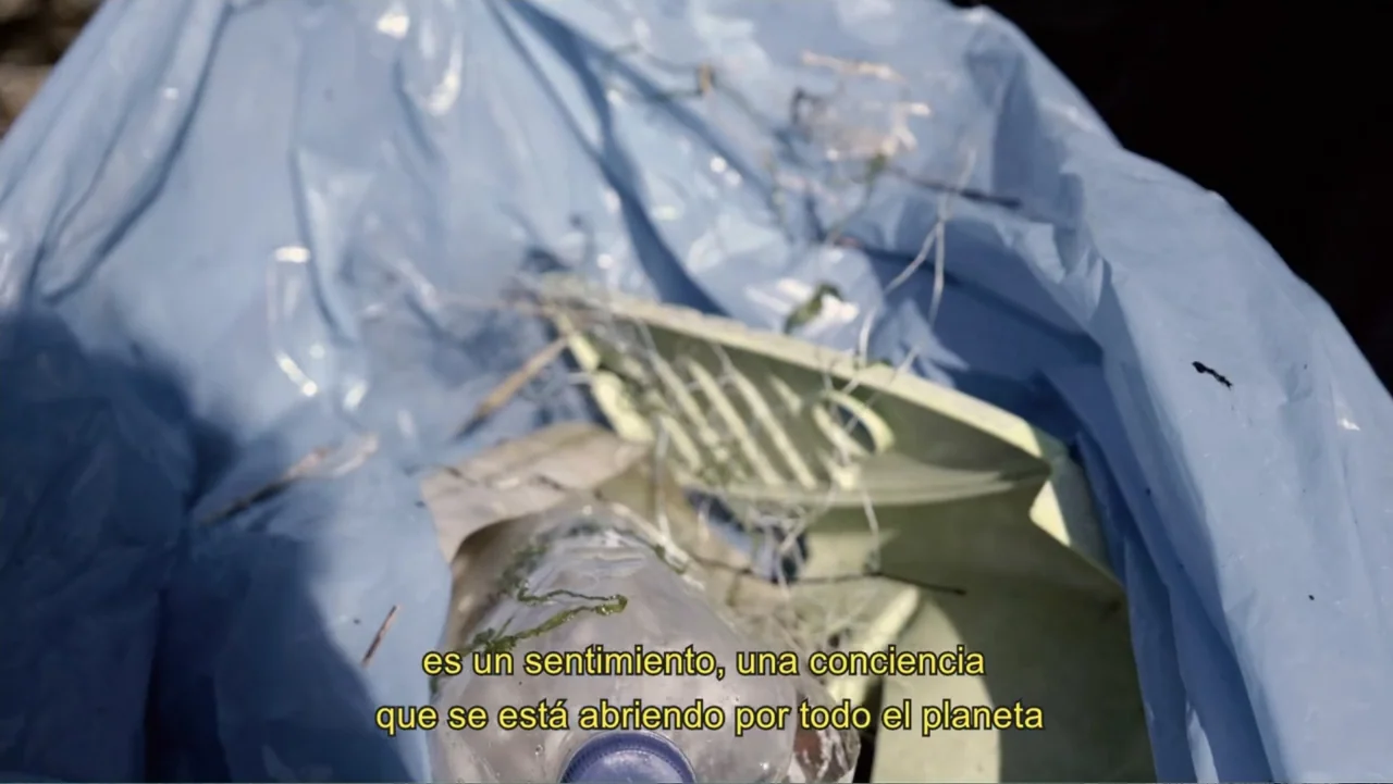 Hondar 2050 (2018) movie still: closeup — A light blue plastic trash bag contains discarded debris and a plastic bottle. The translucent material…