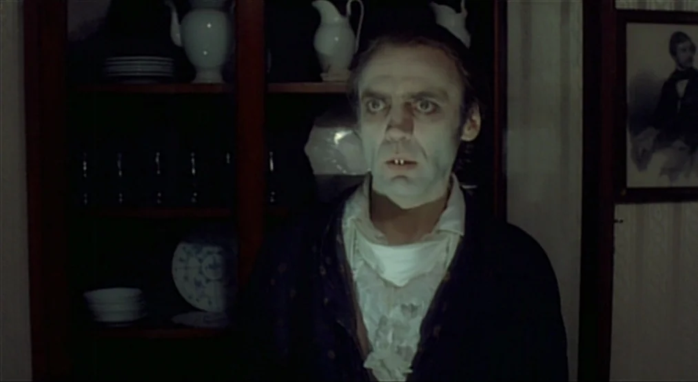 Nosferatu the Vampyre (Nosferatu Phantom Der Nacht) (1979) movie still: medium — A dark, wood-paneled room contains a glass-fronted cabinet filled…