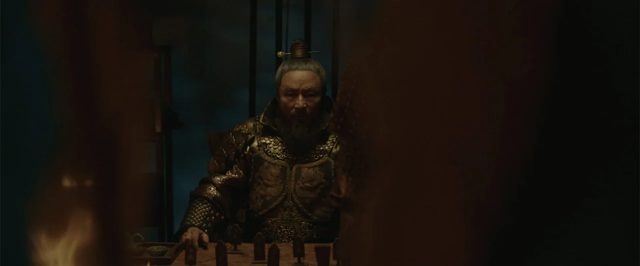 Along with the Gods: The Last 49 Days (2018) movie still: medium — An interior space dimly lit by firelight with dark shadows masking the room…