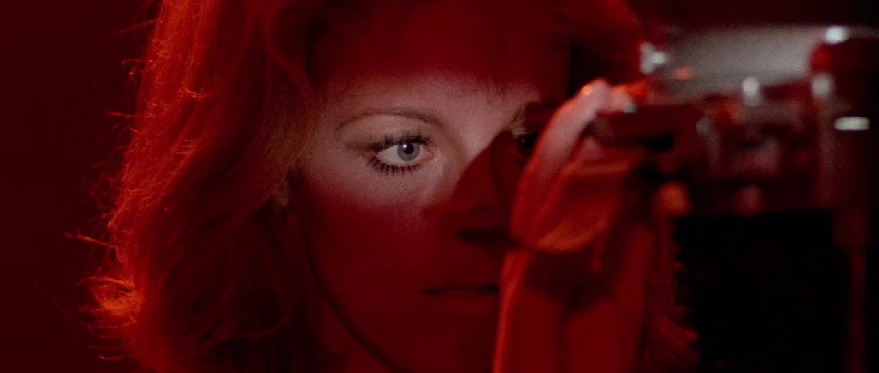 The Case of the Scorpion’s Tail (1971) movie still: closeup — A woman looks through a camera viewfinder in a dark room with red illumination. A…