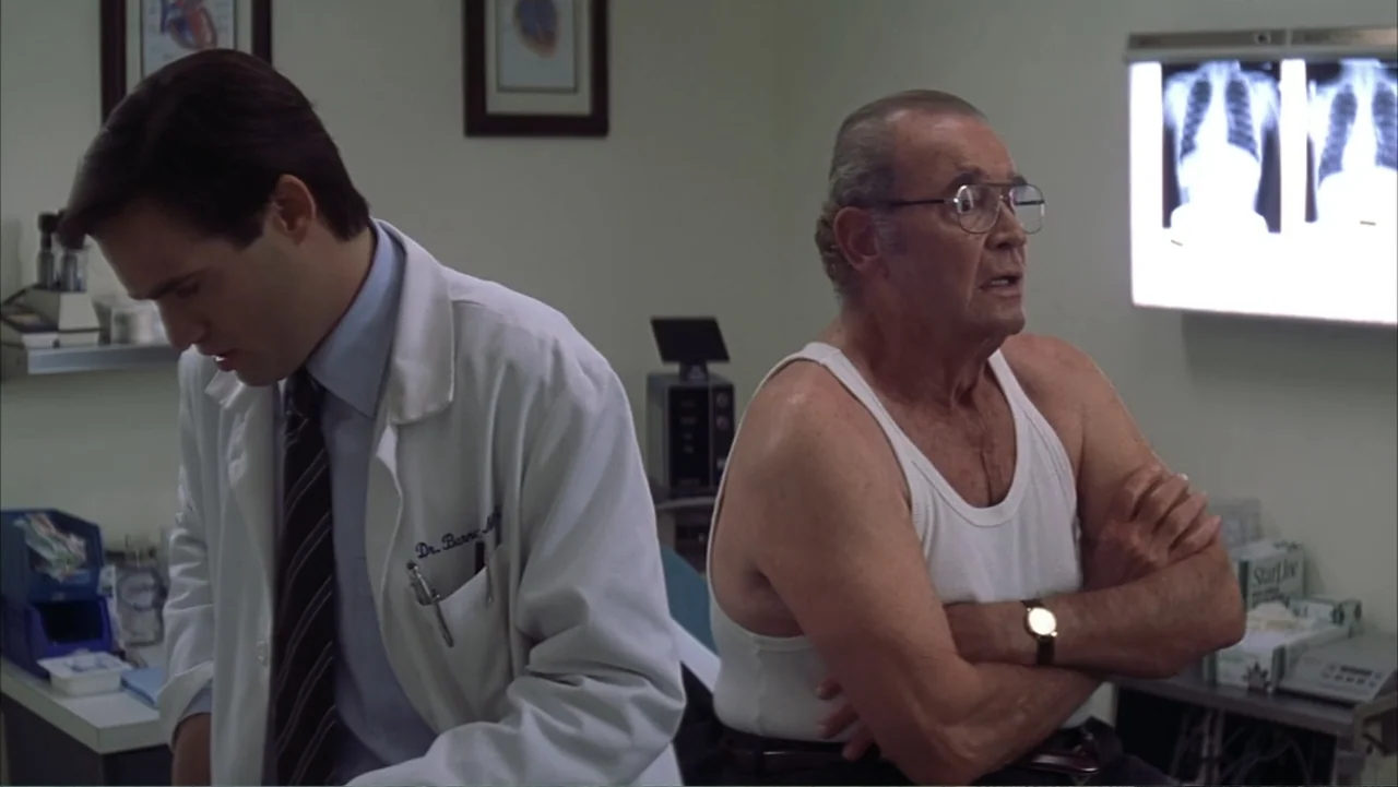 The Notebook (2004) movie still: medium — A medical examination room features wall-mounted X-ray displays and anatomical diagrams. A physician in a…