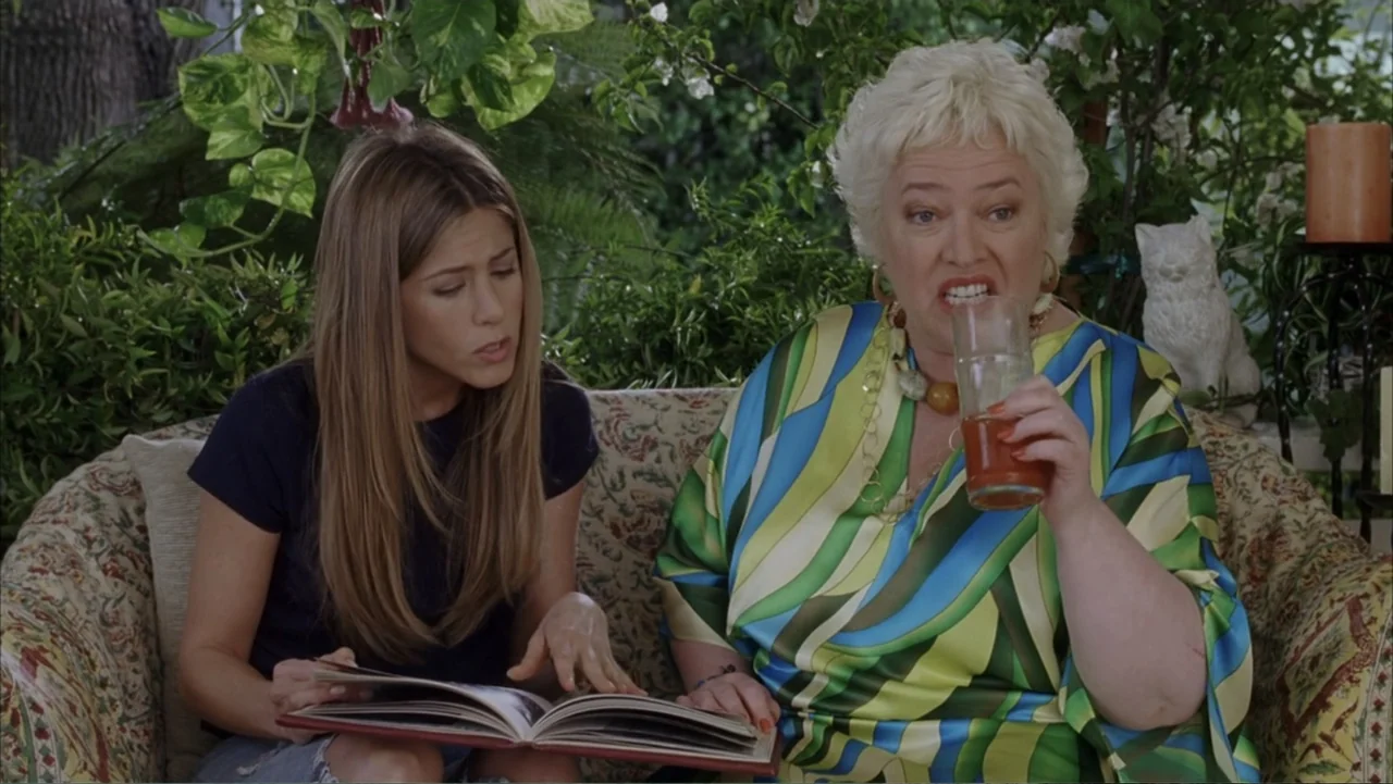 Rumor Has It... (2005) movie still: medium — An outdoor patio area features lush green foliage and a patterned upholstered sofa. Two women sit…