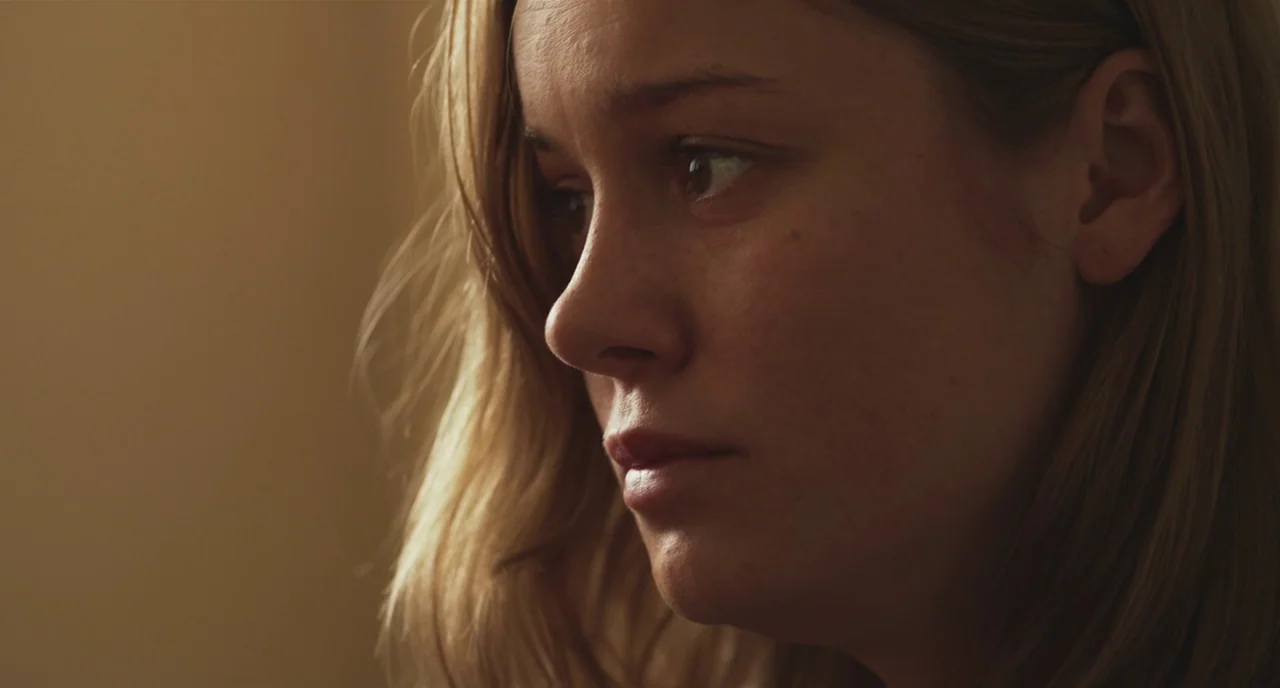 Short Term 12 (2013) movie still: closeup — A close up of a woman in a dimly lit indoor space. She looks ahead with a steady gaze while light hits…