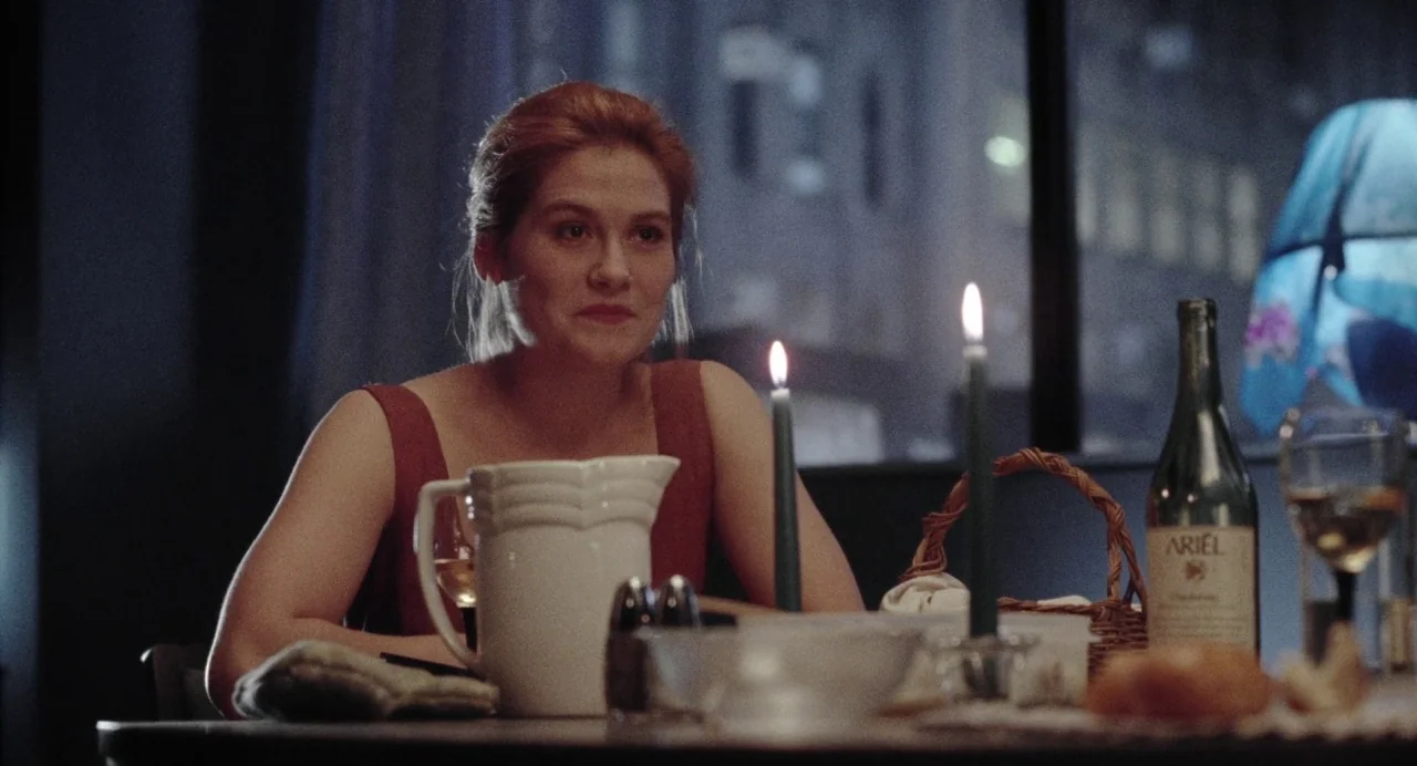 What Happened Was… (1994) movie still: medium — An interior space at night with a city skyline visible through a dark window. A woman sits at a…