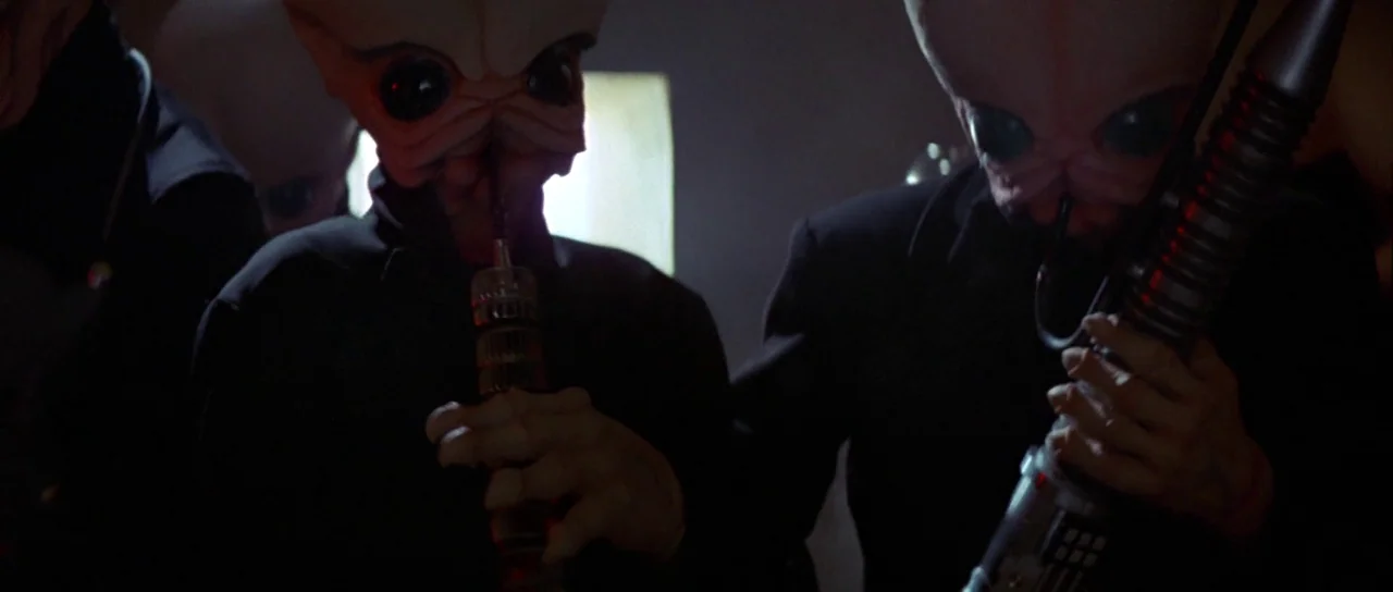 Star Wars (1977) movie still: medium — A dimly lit indoor space with alien musicians performing on metallic instruments. The figures have large…
