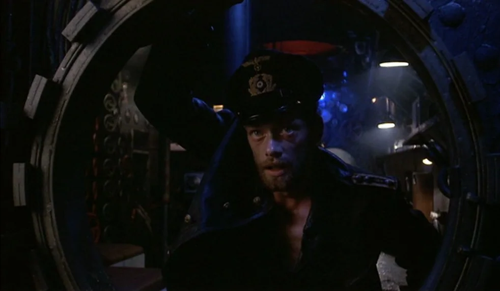 Das Boot (1981) movie still: medium — A cramped, metallic submarine passage features circular bulkheads and dense technical machinery in the…