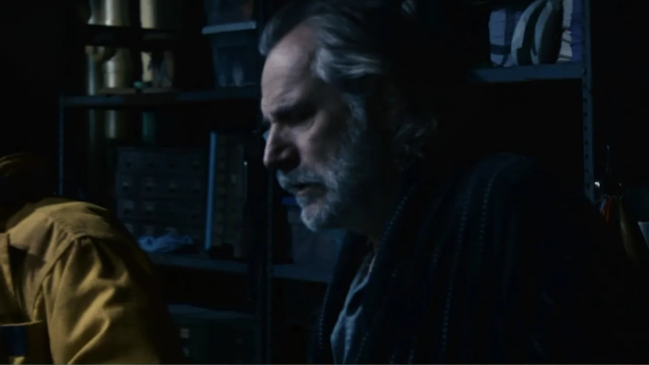 Quarantine (2008) movie still: medium — A dark, cluttered interior storage room contains metal shelving units filled with various stacked items. A…