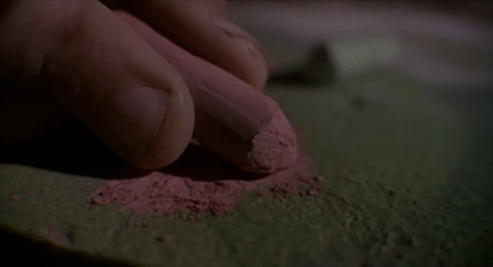 A Nightmare On Elm Street 4: The Dream Master (1988) movie still: closeup — A close-up view shows a dusty pink chalk pastel held against a textured…