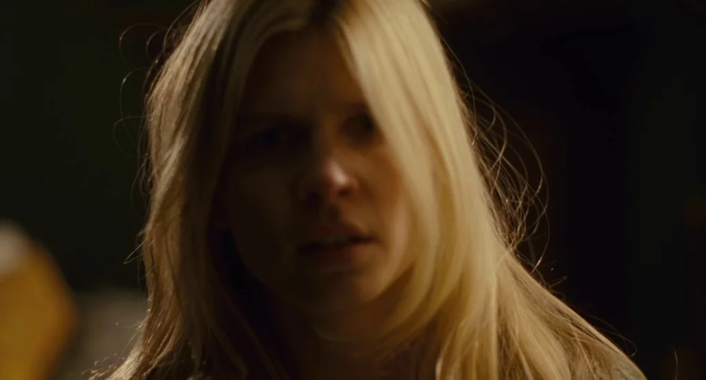 127 Hours (2010) movie still: closeup — An interior space is shrouded in deep shadows with minimal ambient light. A woman with long blonde hair…