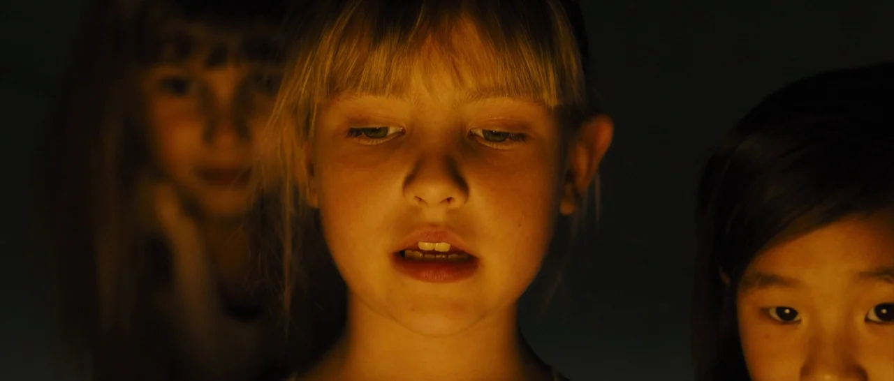 Blade Runner 2049 (2017) movie still: closeup — Three children stand closely together in a space entirely consumed by darkness. An unseen light…
