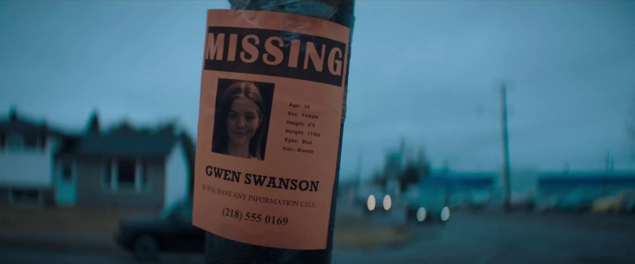 The Silencing (2020) movie still: closeup — A paper missing person flyer is taped to a wooden utility pole outdoors. The background shows a suburban…