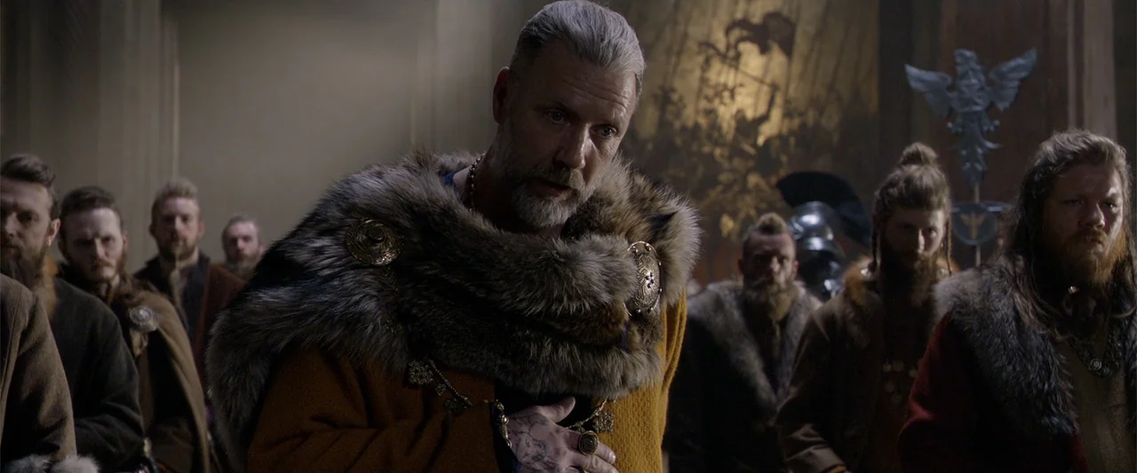 King Arthur: Legend of the Sword (2017) movie still: medium — A stone great hall features wooden carvings and dimly lit, rustic interior…