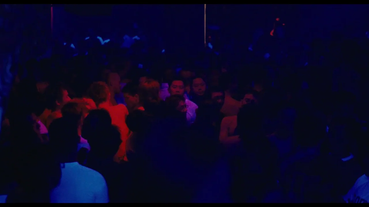 Millennium Mambo (2001) movie still: wide — A dense, dark crowd of people fills a low-light space. The room is illuminated by flickering red and…