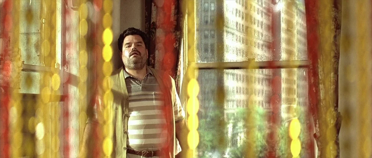 Léon: The Professional movie still: medium — A man stands in an apartment room bathed in warm sunlight through a window. The foreground is partially…
