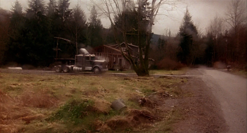Twin Peaks: Fire Walk With Me (1992) movie still: wide — A rural landscape features a gravel road beside a weathered, wooden-framed house. A…
