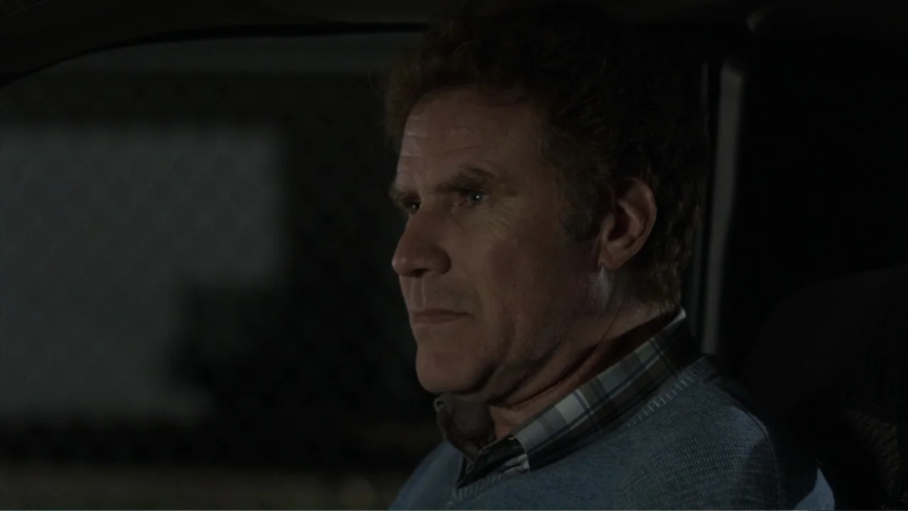 Get Hard (2015) movie still: closeup — A dark interior of a vehicle at night with blurred shapes visible through the window. A man sits in the…