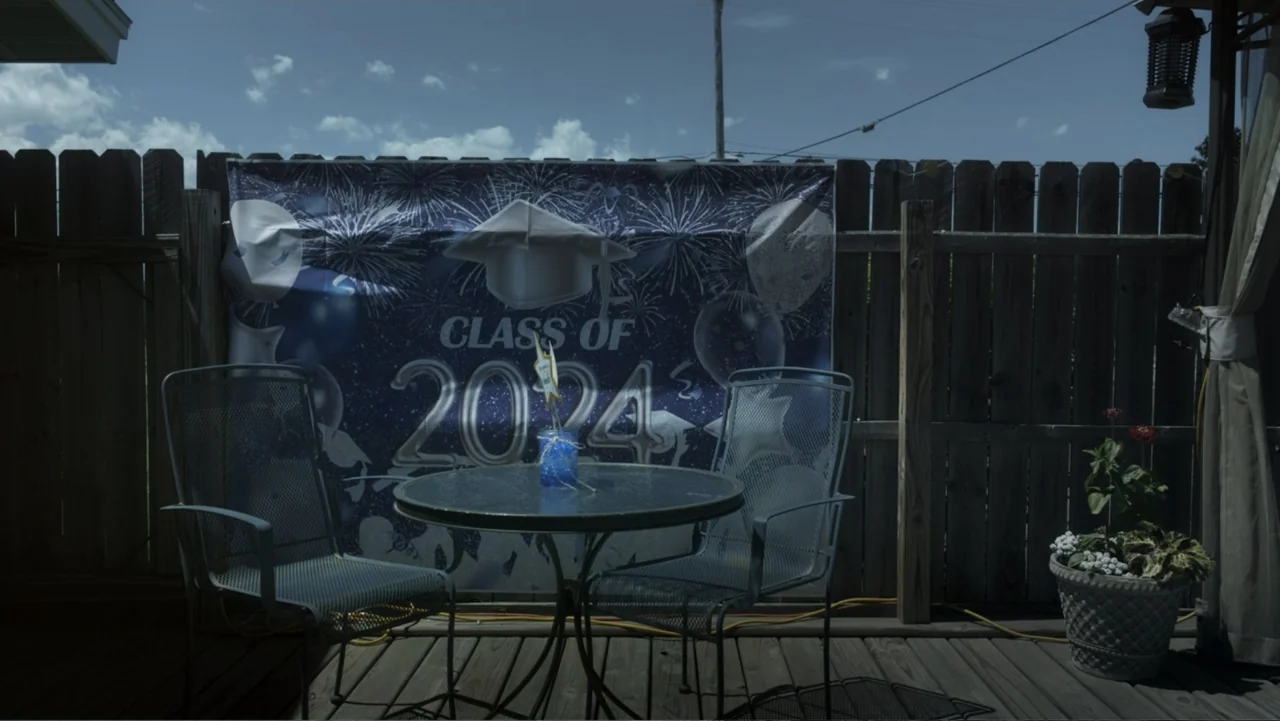 Predators (2010) movie still: medium — A backyard wooden deck features a small circular table and two metal chairs. A blue banner celebrating the…