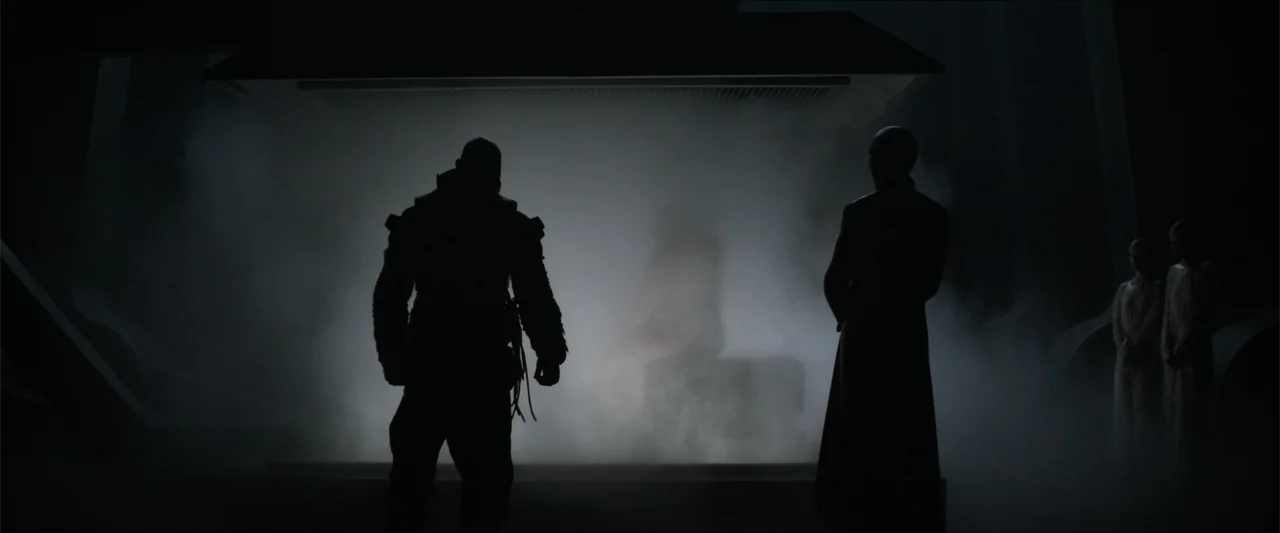 Dune (2021) movie still: fullbody — A dark, expansive industrial space is filled with thick rolling fog and haze. Four figures stand in dark…