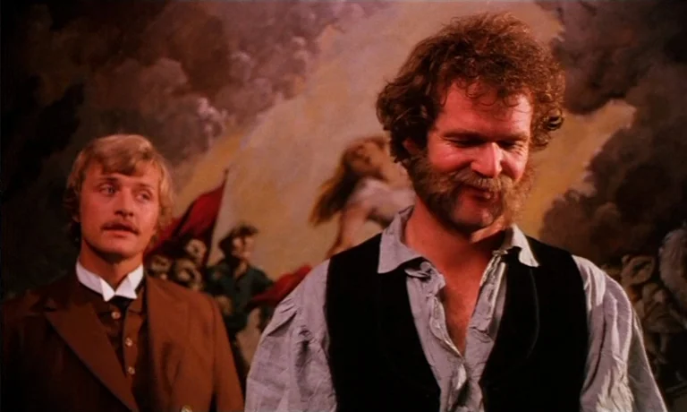 Katie Tippel (1975) movie still: medium — Two men stand before a large, expansive oil painting depicting a historical battle scene. The taller man…