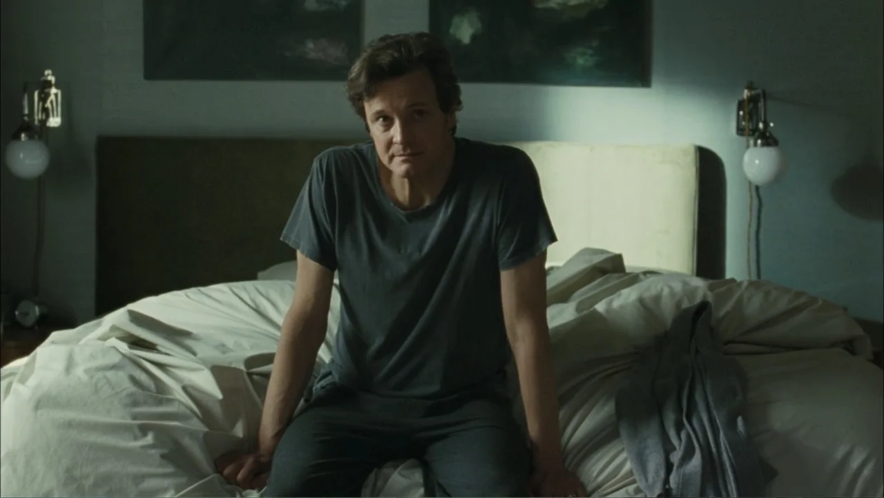 Before I Go to Sleep (2014) movie still: medium — A dimly lit room contains a large unmade bed with light colored linens. A middle aged man sits…