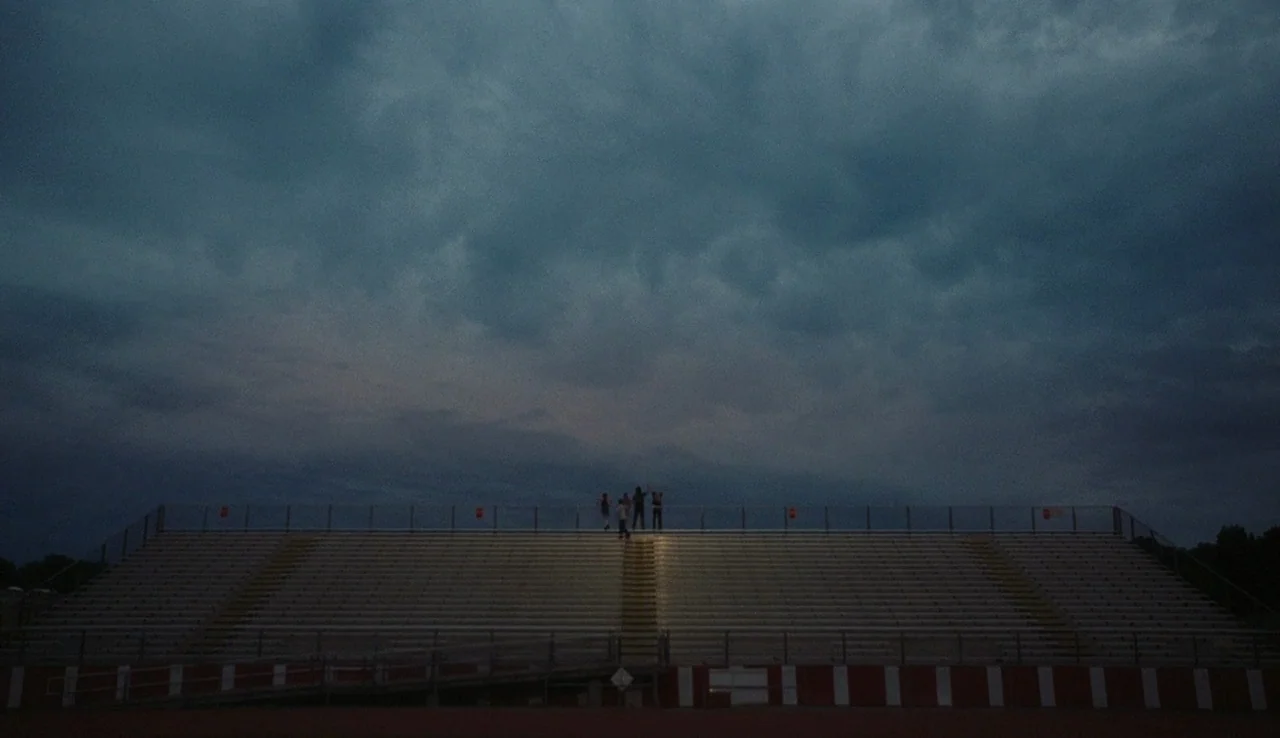 The Perks of Being A Wallflower (2012) movie still: establishing — A set of empty stadium bleachers sits against a vast, dark, cloud-filled twilight…