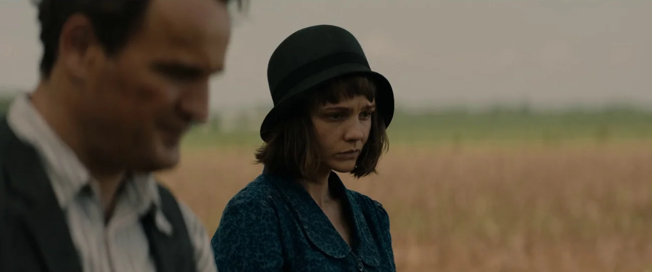 Mudbound (2017) movie still: medium — A woman and a partially visible man stand in a wide, dry agricultural field. The sky is overcast and the…