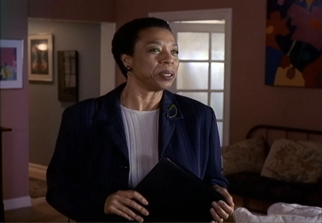 Chance of a Lifetime (1998) movie still: medium — A residential room features dark reddish-brown walls decorated with framed artwork. A middle-aged…