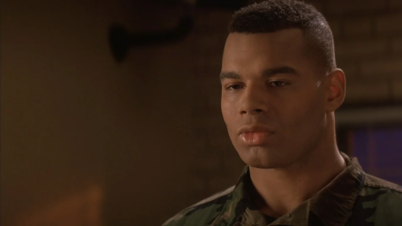 A Few Good Men (1992) movie still: closeup — A dimly lit interior room features blurred brick elements in the background shadows. A man in a…