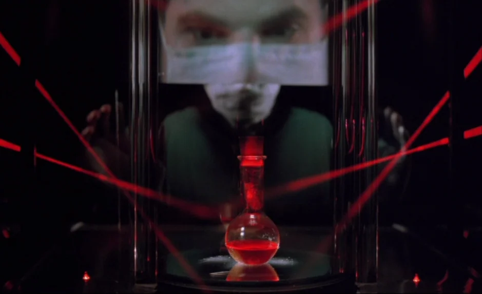 Mauvais Sang (Bad Blood) (The Night Is Young) (1986) movie still: medium — A dark, clinical setting features a glowing red liquid inside a small…