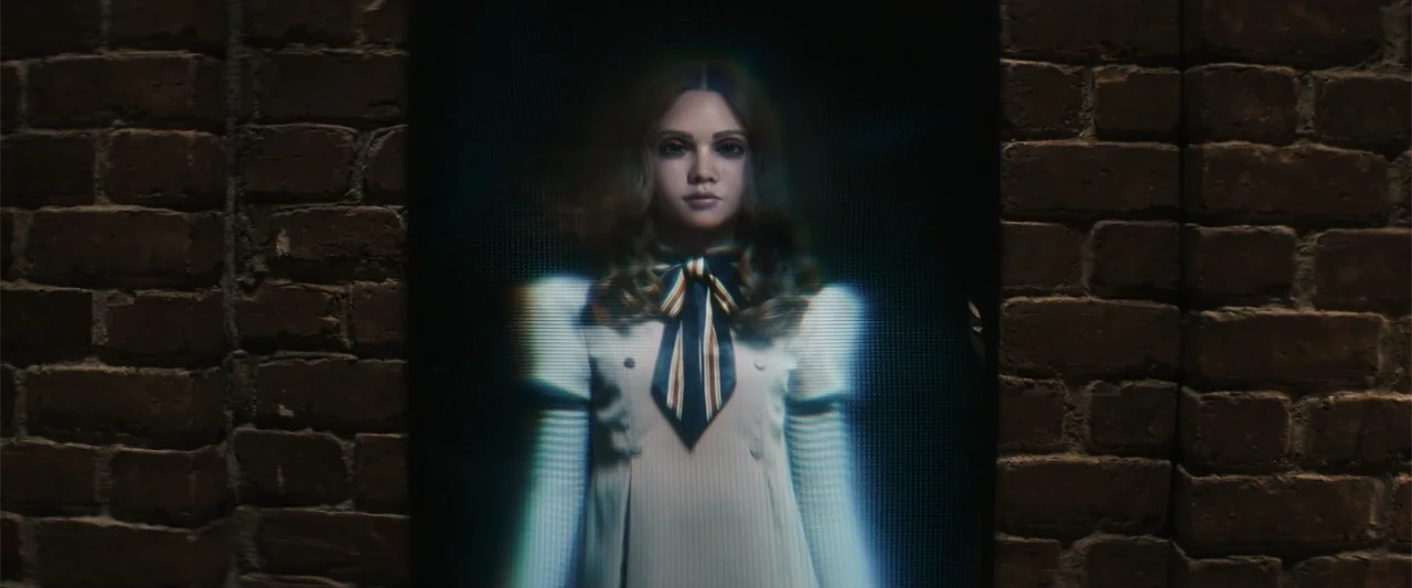 M3GAN 2.0 (2025) movie still: medium — A digital screen displays a person against a dark, textured brown brick wall backdrop. The figure is centered…