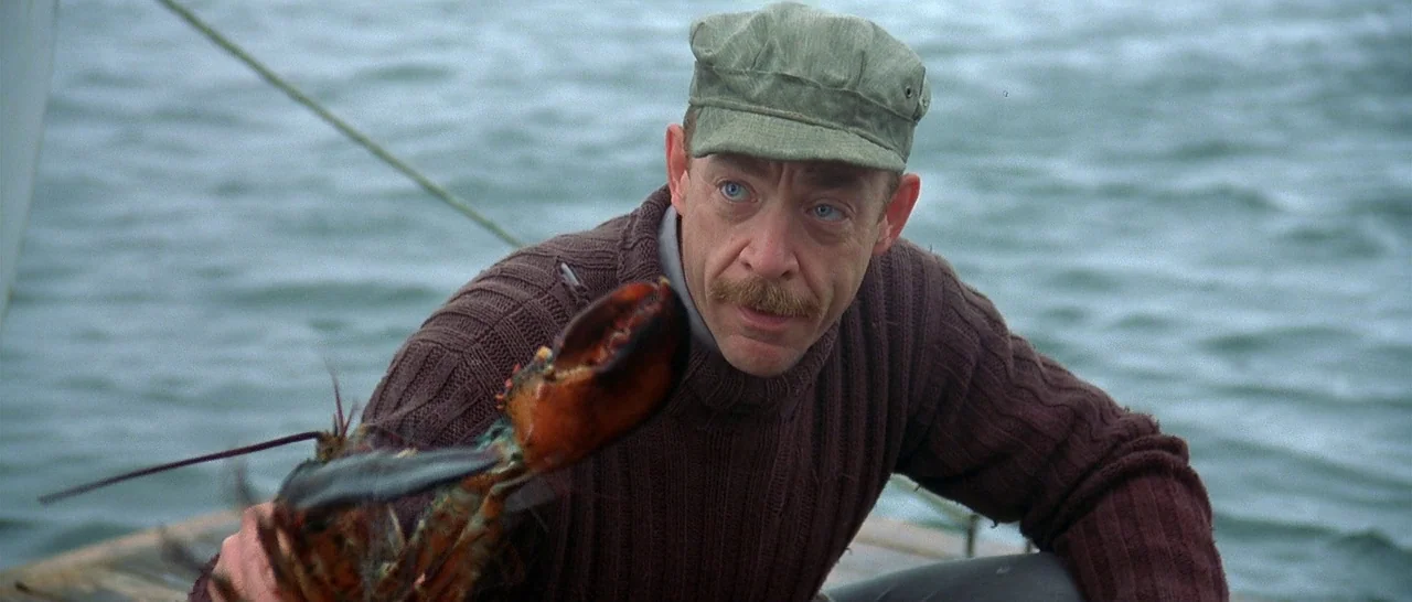 The Cider House Rules movie still: medium — A man stands on a boat deck with water visible in the background. The man holds a large lobster out…