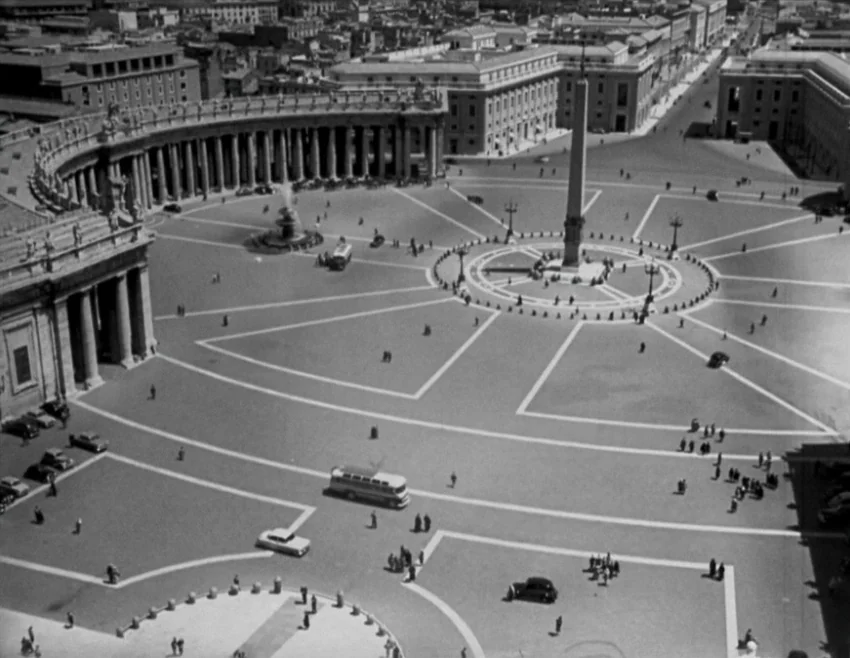 Roman Holiday (1953) movie still: establishing — An aerial view captures the vast expanse of St. Peter's Square with its colonnades. Tiny figures…