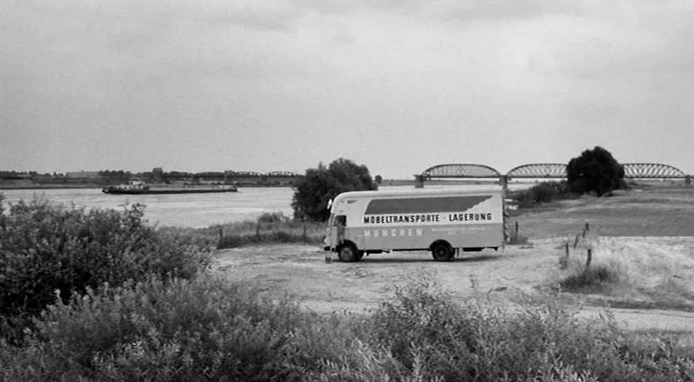 Kings of the Road (Im Lauf der Zeit) (1976) movie still: wide — A rural riverbank landscape features a large box truck parked on bare dirt. A metal…