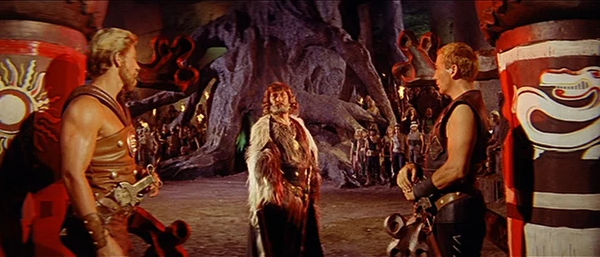 Erik The Conqueror (1961) movie still: fullbody — A dark subterranean space features large carved pillars decorated with painted sun and dragon…