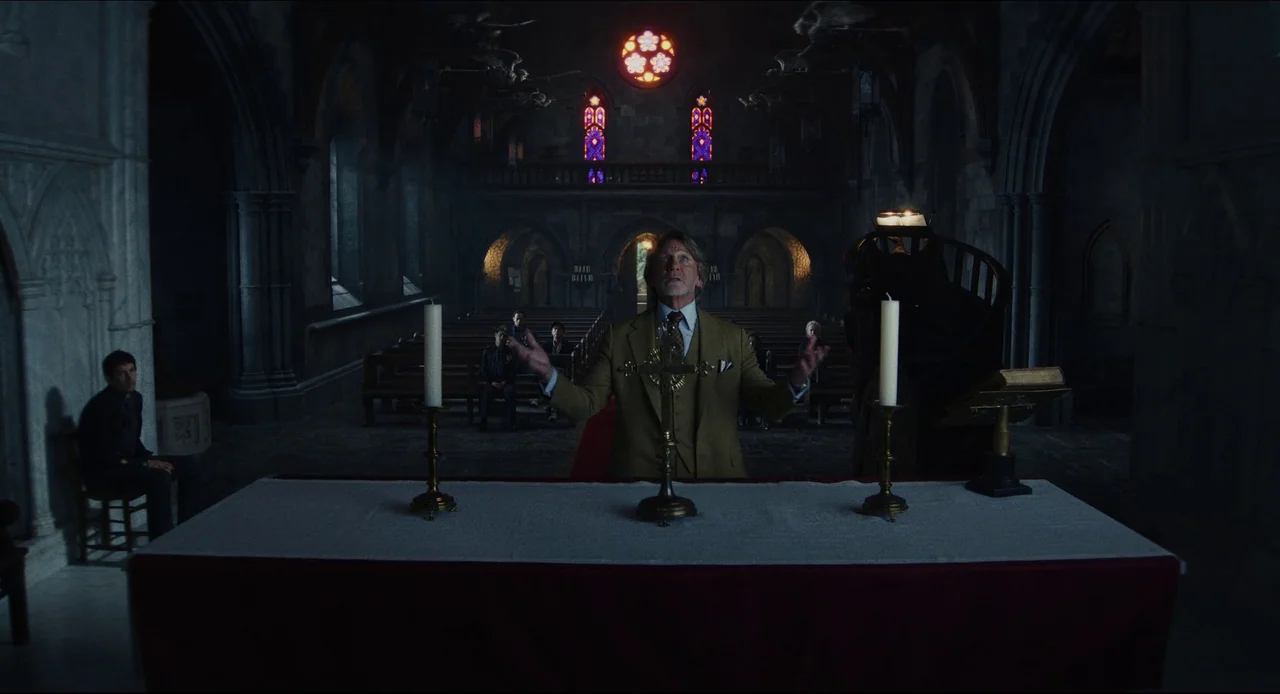 Wake Up Dead Man (2025) movie still: medium — A dark stone church interior features high ceilings with glowing stained glass windows above. A man in…