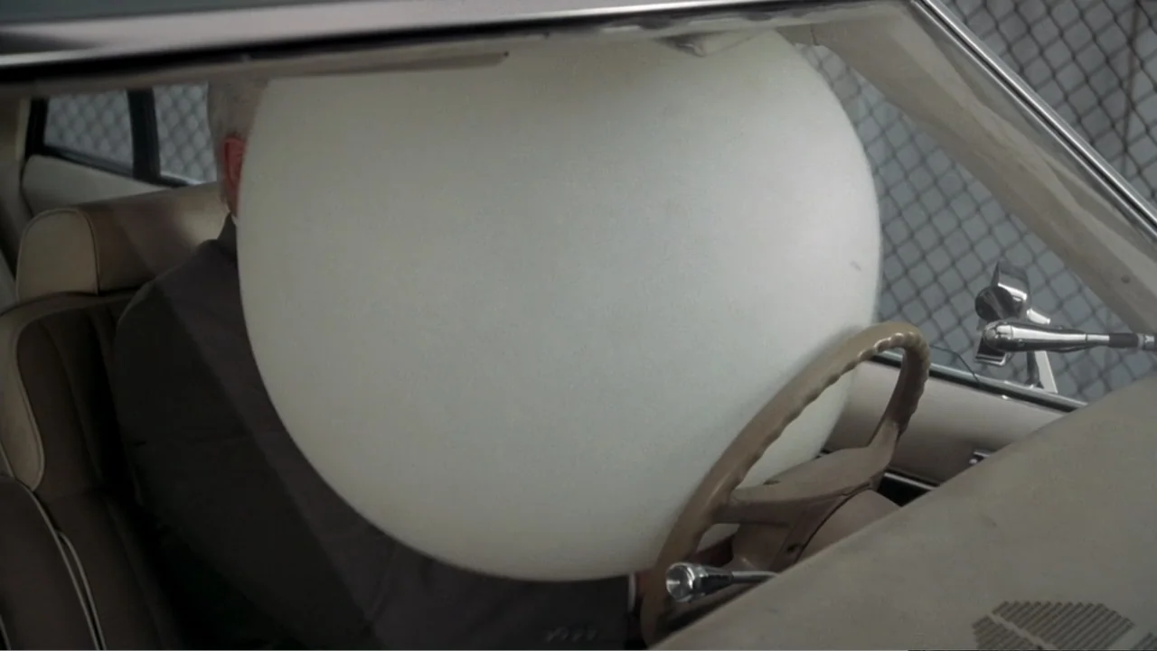 The Naked Gun: From the Files of Police Squad! (1988) movie still: medium — The interior of a sedan with tan upholstery and a deployed circular…