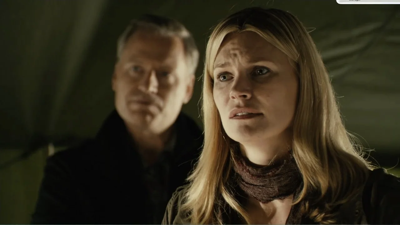 National Parks Adventure (2016) movie still: medium — A dark interior space with green canvas walls visible behind two people. A woman stands in the…