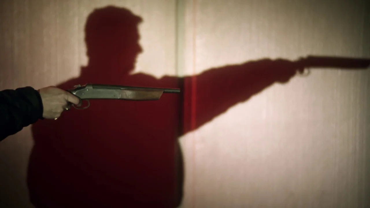 Chopper (2000) movie still: medium — A plain wall serves as a backdrop for a large, projected shadow. A hand holds a shotgun, matching the…