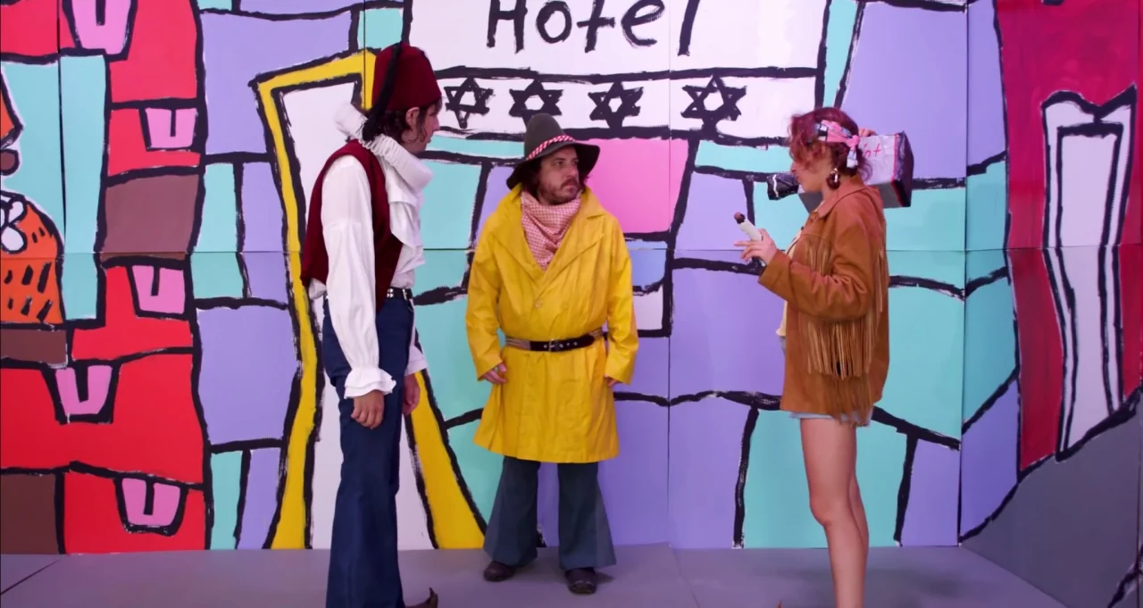 Adam Green’s Aladdin (2016) movie still: fullbody — A theatrical studio set features a painted two-dimensional backdrop of a hotel exterior. Three…