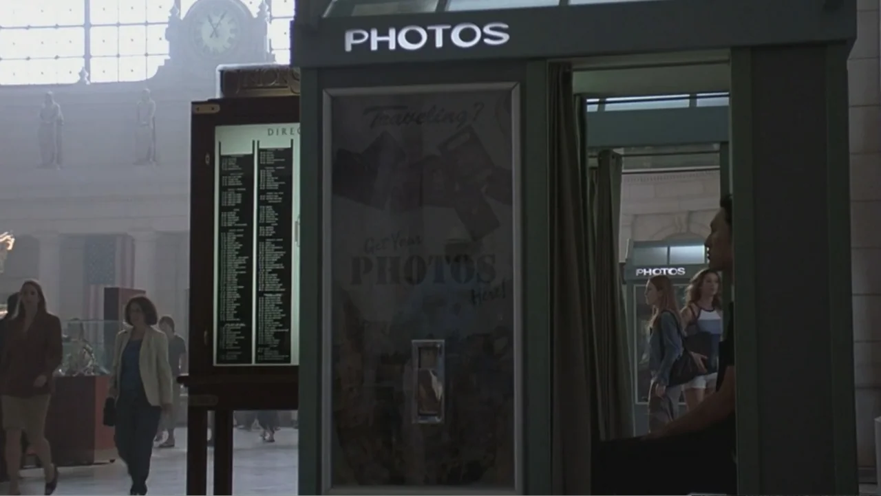 Hannibal (2001) movie still: medium — A spacious transit hall features high ceilings and a large central clock on the wall. A man sits inside a…