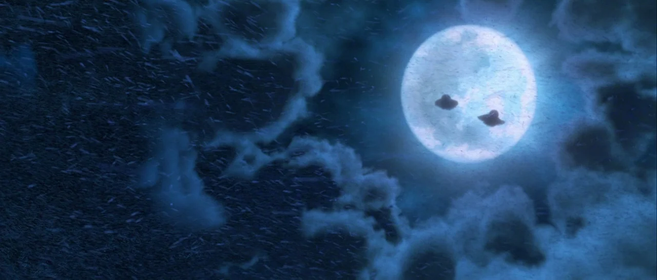 Kubo and the Two Strings movie still: establishing — A night sky filled with dark, swirling clouds and a bright glowing moon. Two small disc-shaped…