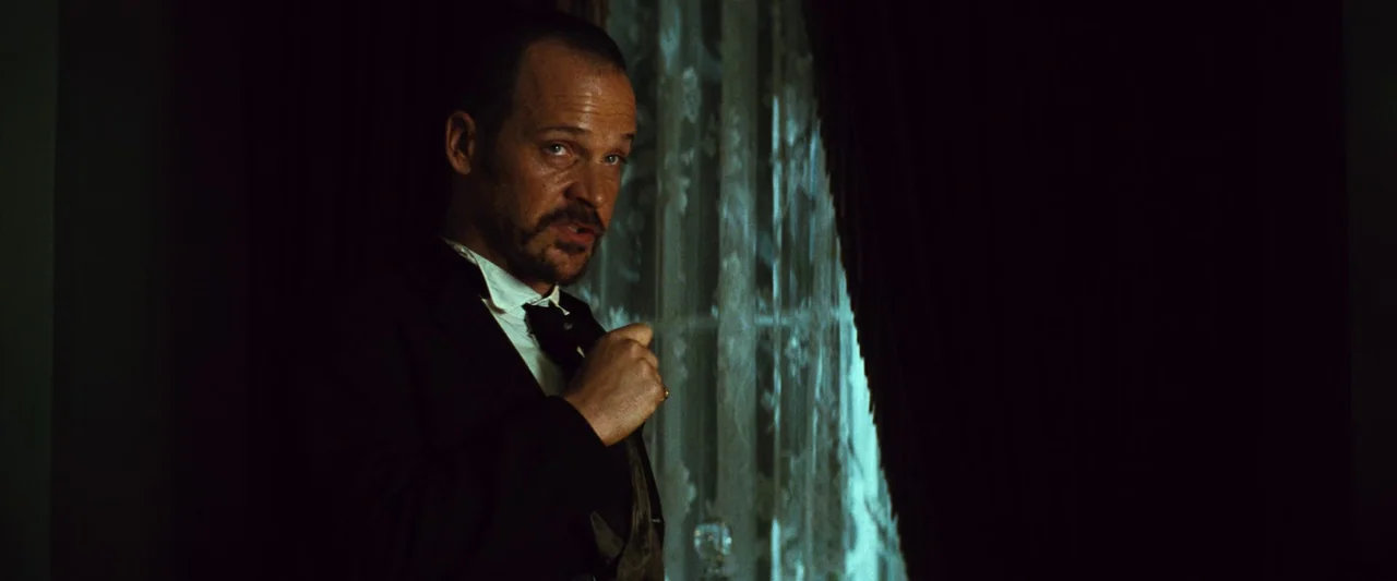 The Magnificent Seven (2016) (2016) movie still: medium — A dark indoor space features heavy curtains flanking a bright window with sheer lace. A…