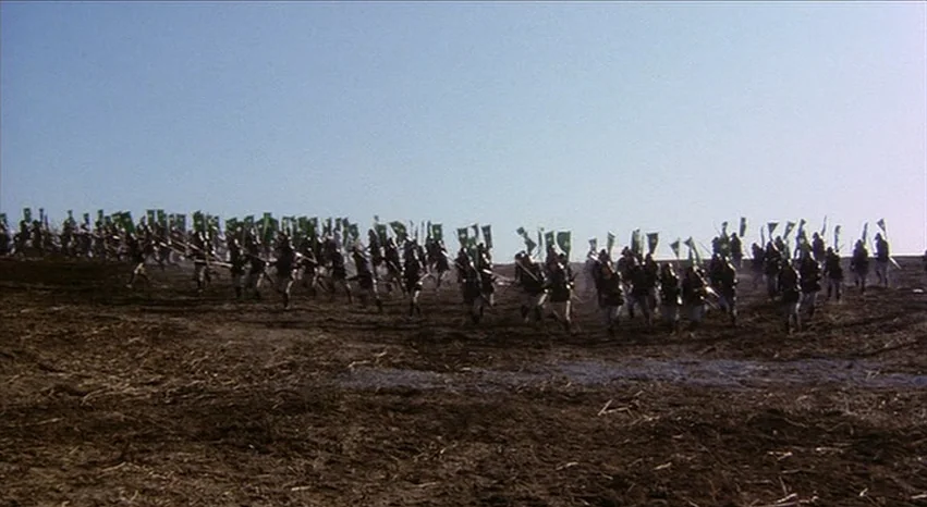 Kagemusha (1980) movie still: wide — A vast, barren dirt field stretches toward a clear, pale horizon under bright sunlight. Many soldiers in…