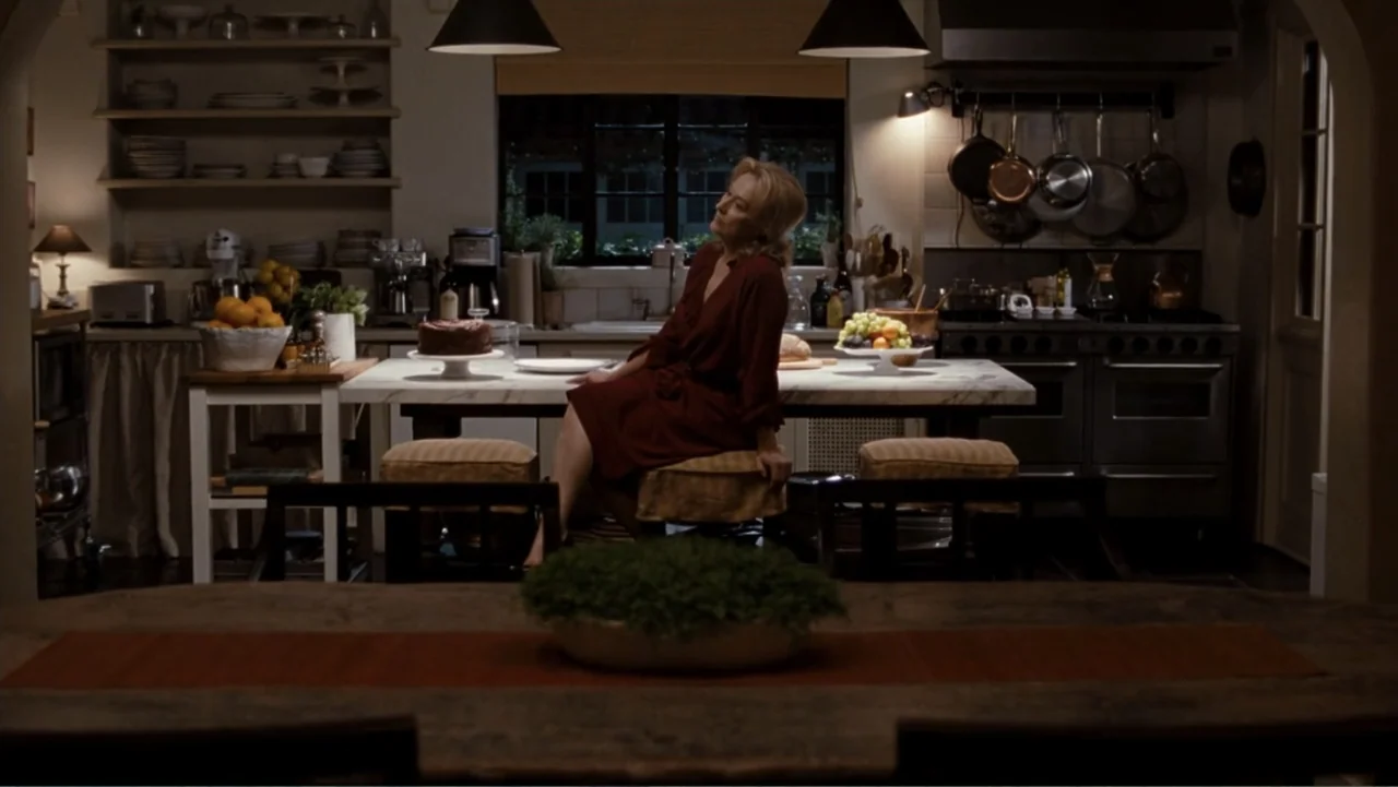 It's Complicated (2009) movie still: medium — A spacious, well-lit residential space with open shelving, marble island, and dark wooden cabinets. A…