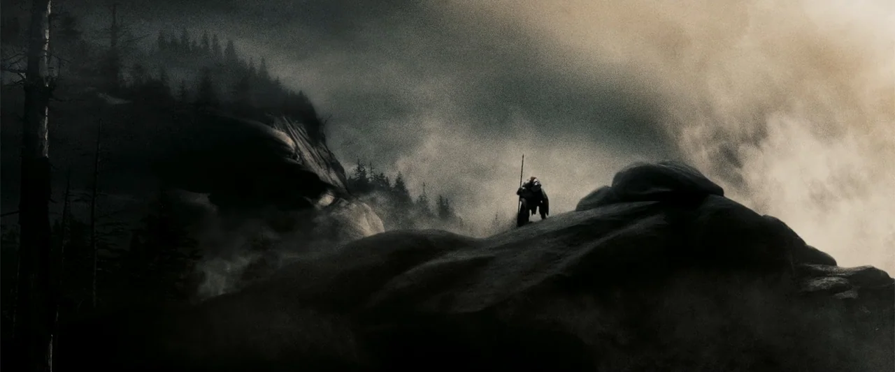 300 (2007) movie still: wide — A rugged mountain landscape is shrouded in dense atmospheric mist and dark, jagged rocks. A lone warrior silhouette…