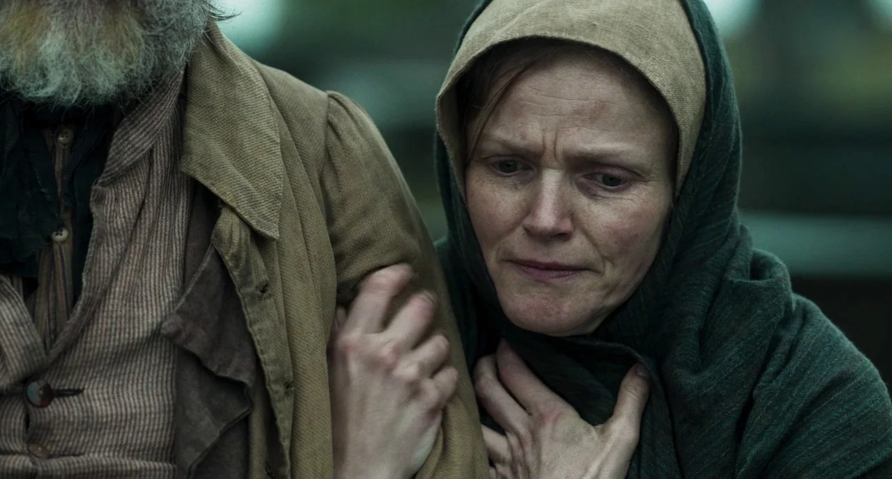 Peterloo (2018) movie still: medium — A rural setting features an older man in period clothing beside a woman. The woman grasps her own shawl while…